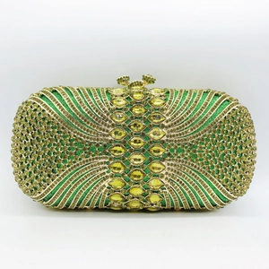 Detailed close-up of emerald green crystal evening clutch bag with gold flower clasp