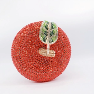 Detailed view of apple-shaped evening clutch with red rhinestones and golden leaf clasp