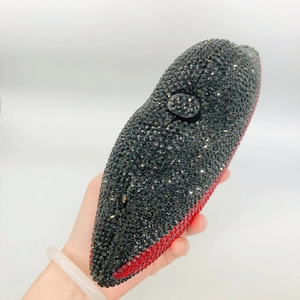 Détail d'une pochette de soirée en forme de lèvres avec cristaux rouges et noirs scintillants