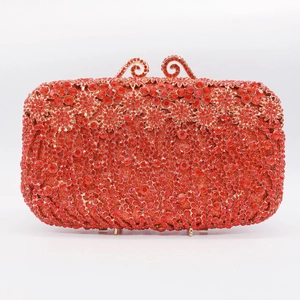Close-up of red rhinestone clutch bag featuring a detailed gold dual-swirl clasp