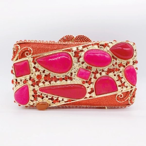 Close-up of red rhinestone clutch bag featuring large pink gems and gold metal frame