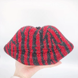 Detailed close-up of sparkling red and black rhinestone lip clutch bag held in hand