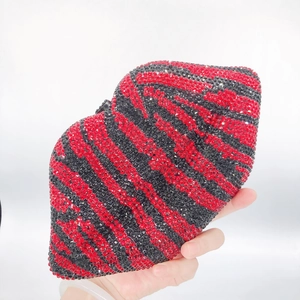 Lip-shaped clutch bag with red and black zebra pattern rhinestones held by hand