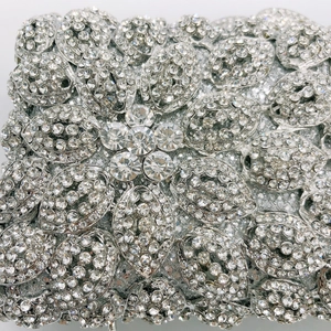 Macro detail of silver clutch evening bag featuring radial pattern of inlaid white rhinestones