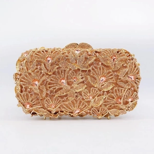 Close-up of golden evening clutch with pink rhinestones and floral hollow patterns