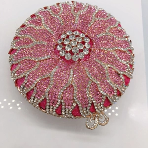 Detail of a round sunburst evening clutch with pink crystals and a bow clasp
