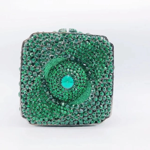 Close-up of green rhinestone clutch bag featuring a central emerald-style gem and pattern