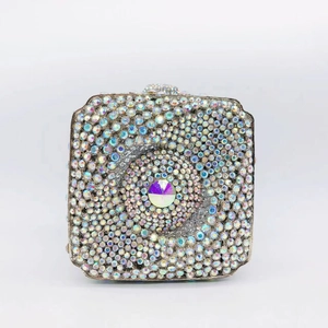 Detailed view of silver square clutch bag with iridescent rhinestones and large central crystal