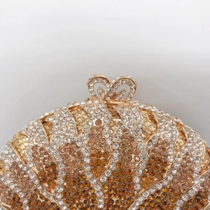 Macro detail of sunburst crystal clutch bag featuring golden base and amber rhinestones
