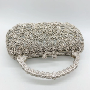 Macro detail of silver clutch bag with floral rhinestone pattern and crystal handle