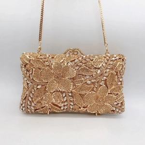 Dettaglio di borsa da sera dorata con elaborati motivi floreali in strass e catena sottile