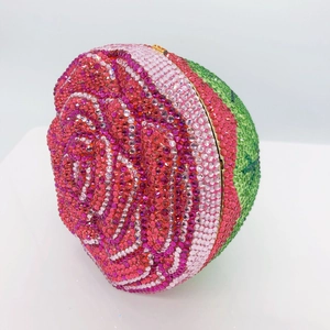 Detail of rose-shaped clutch with red and pink rhinestones in gold metal frame