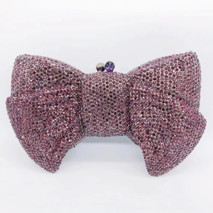 Macro shot of bow-shaped evening clutch bag with deep purple rhinestones and gem clasp