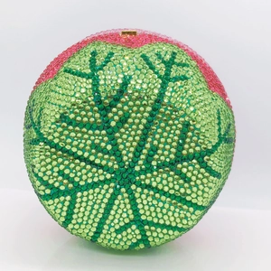 Macro view of crystal encrusted spherical evening clutch with green gradient finish