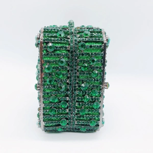 Macro shot of emerald green rhinestones and crystal studs on a luxury metal frame clutch