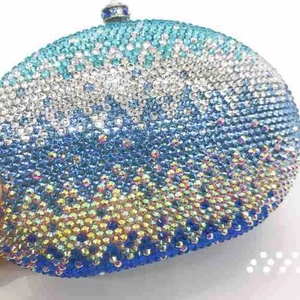 Macro shot of gradient blue rhinestones and gemstone clasp on oval evening clutch