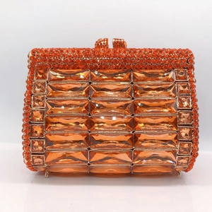 Detailed close-up of orange rhinestones and gold metal frame on luxury clutch purse