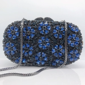 Detailed macro of the sparkling blue rhinestone floral pattern on a black evening clutch bag