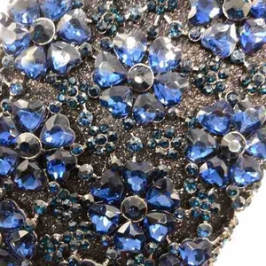 Macro detail of dark blue crystal heart and flower pattern on luxury evening clutch bag