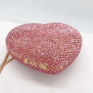 Detailed view of heart-shaped pink crystal evening clutch with golden metal chain