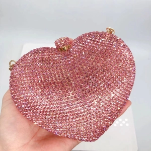 Close-up of pink heart clutch bag with shimmering crystals and gold metal frame details