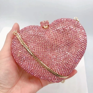 Close-up of pink heart-shaped clutch bag with luxury rhinestones and gold chain