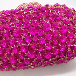 Close-up of luxury rose pink rhinestones and gold metal trim on elegant evening clutch bag