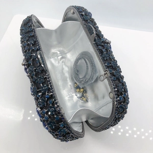 Detail of evening clutch interior with silver lining, chain strap, and spare rhinestones