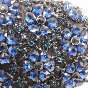 Close-up of blue heart-shaped rhinestones and floral crystals on a sparkling clutch bag