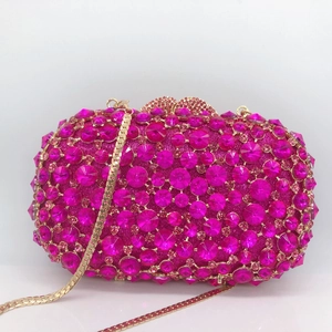 Close-up of fuchsia rhinestone evening clutch with gold chain and studded metal frame