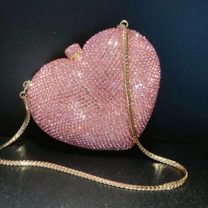 Detail of pink crystal heart clutch bag with shiny rhinestones and gold chain strap