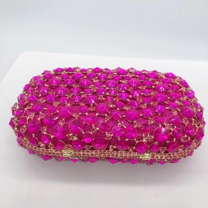 Close-up of rose red evening clutch bag with sparkling crystals and gold metal clasp