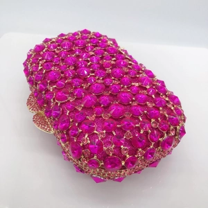 Close-up of fuchsia crystal evening bag with gold metal frame and bow clasp