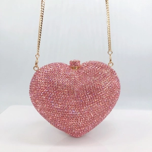 Detail of pink heart-shaped crystal clutch with sparkling rhinestones and gold chain strap