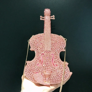 Detailed close-up of pink rhinestone violin-shaped clutch with gold chain strap