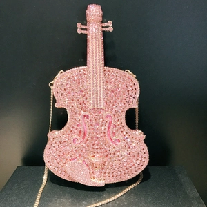 Detailed view of pink rhinestone violin-shaped evening bag with a sleek gold chain