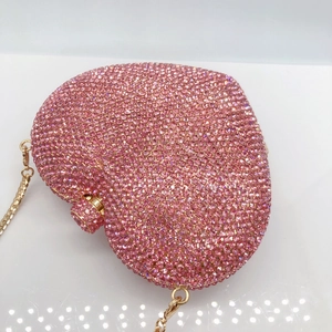 Close-up detail of heart-shaped evening clutch with pink rhinestones and gold chain