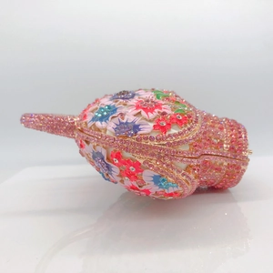 Gros plan détaillé d'un sac de soirée en coquillage avec cristaux roses et fleurs en émail