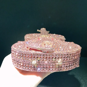 Close-up of pink crystal violin clutch bag with red velvet lining and metal hardware