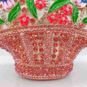 Détails de fleurs en émail et de strass roses sur une pochette de soirée panier