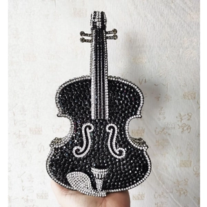 Detailed handheld view of a violin shaped evening clutch bag with black and white rhinestones