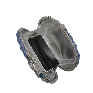 Detail showing internal capacity of blue floral rhinestone evening clutch with phone inside
