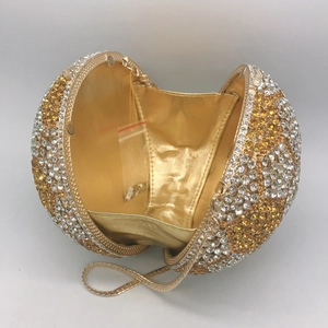 Macro view of crystal encrusted football clutch bag with golden lining and metal chain strap