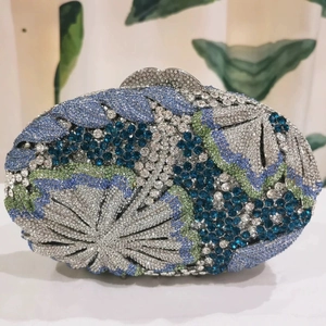 Macro detail of intricate blue and green floral rhinestone patterns on an oval evening clutch