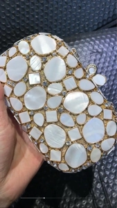 Detail of shell clutch bag featuring white mother of pearl inlay and floral crystal clasp