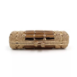 Luxurious cylindrical gold clutch bag with sparkling rhinestones and brown gemstones