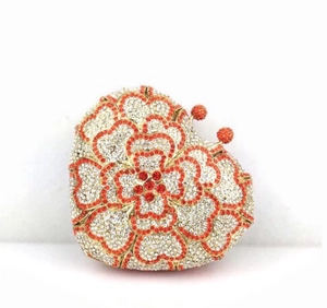 Macro shot of heart-shaped clutch bag with luxury rhinestones and orange floral pattern