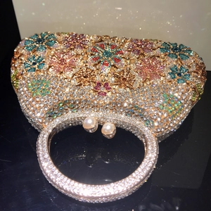 Close-up of luxury floral rhinestone clutch with a crystal ring handle and pearl clasp