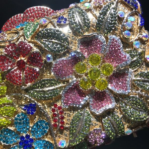 Macro detail of colorful floral rhinestone arrangement on luxury gold evening clutch bag