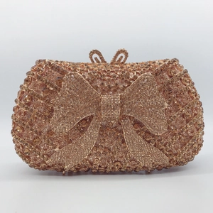 Close-up of rose gold bow-shaped clutch bag with sparkling crystals and metal clasp